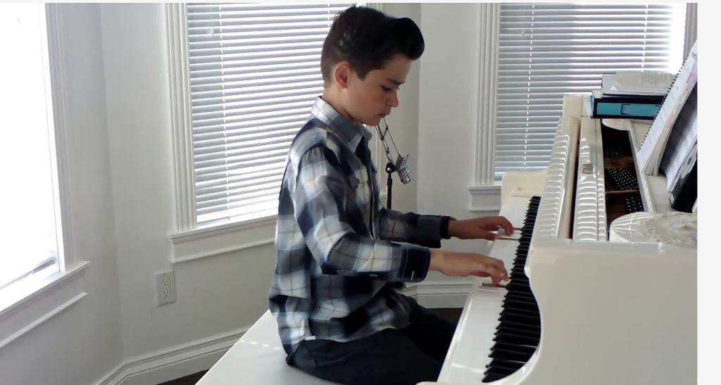 Young student playing piano by bright windows